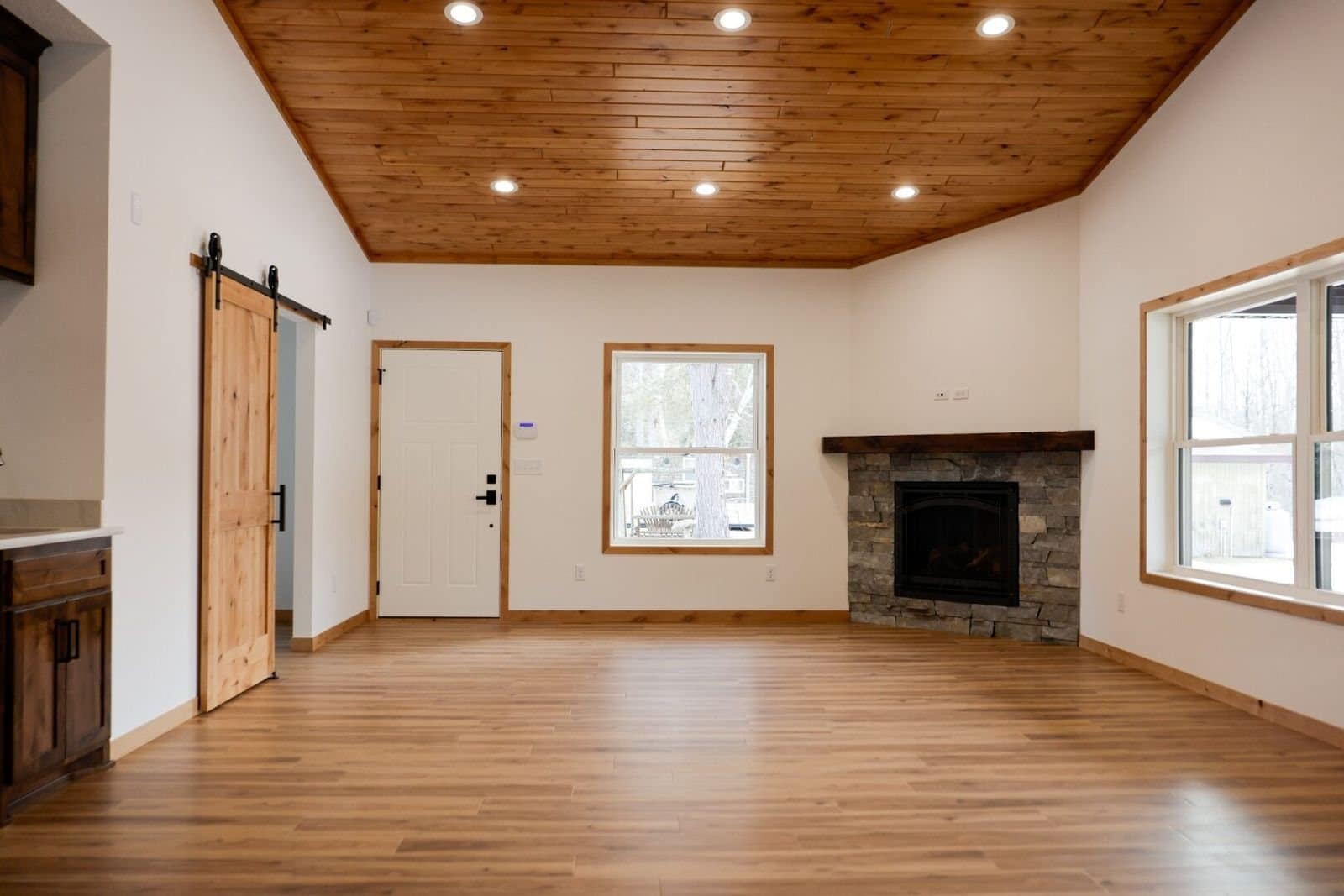Great room with a cedar plank ceiling, a stone fireplace and a sliding barn door
