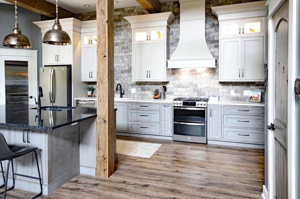 Kitchen with gray shaker cabinets, a granite island and a stacked stone backsplash