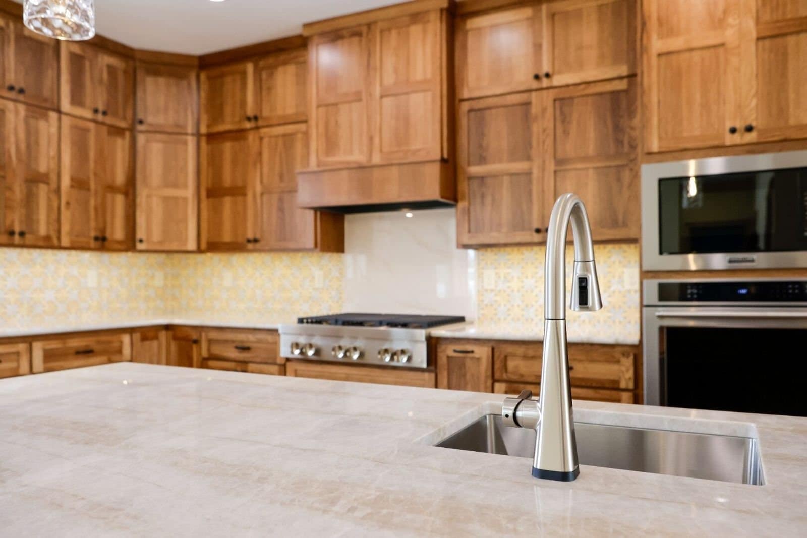 Kitchen with hickory cabinets, a quartzite island and a patterned tile backsplash