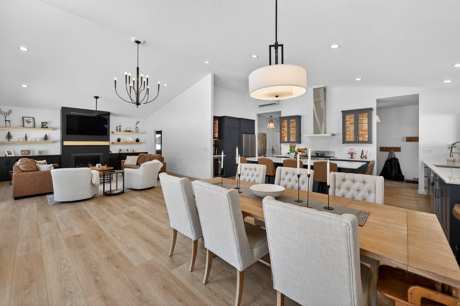 Open plan great room and dining area with navy cabinets and wide plank flooring