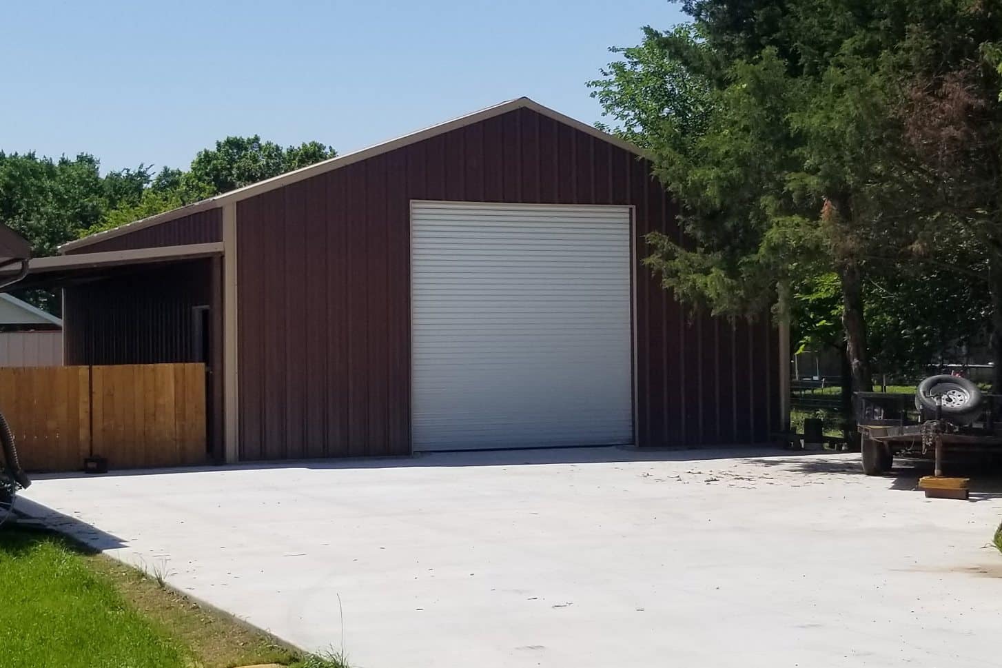 attached shop brown metal roll up door lean to and concrete apron