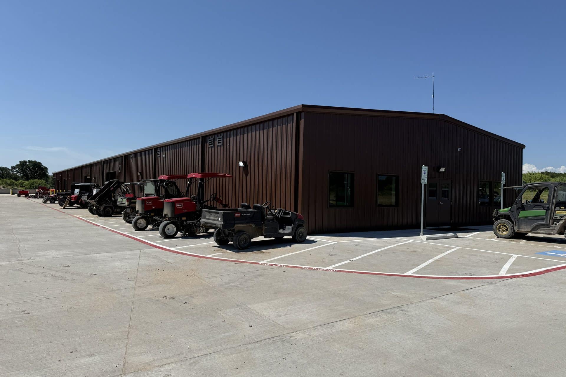 grounds equipment storage building with turf fleet parked outside