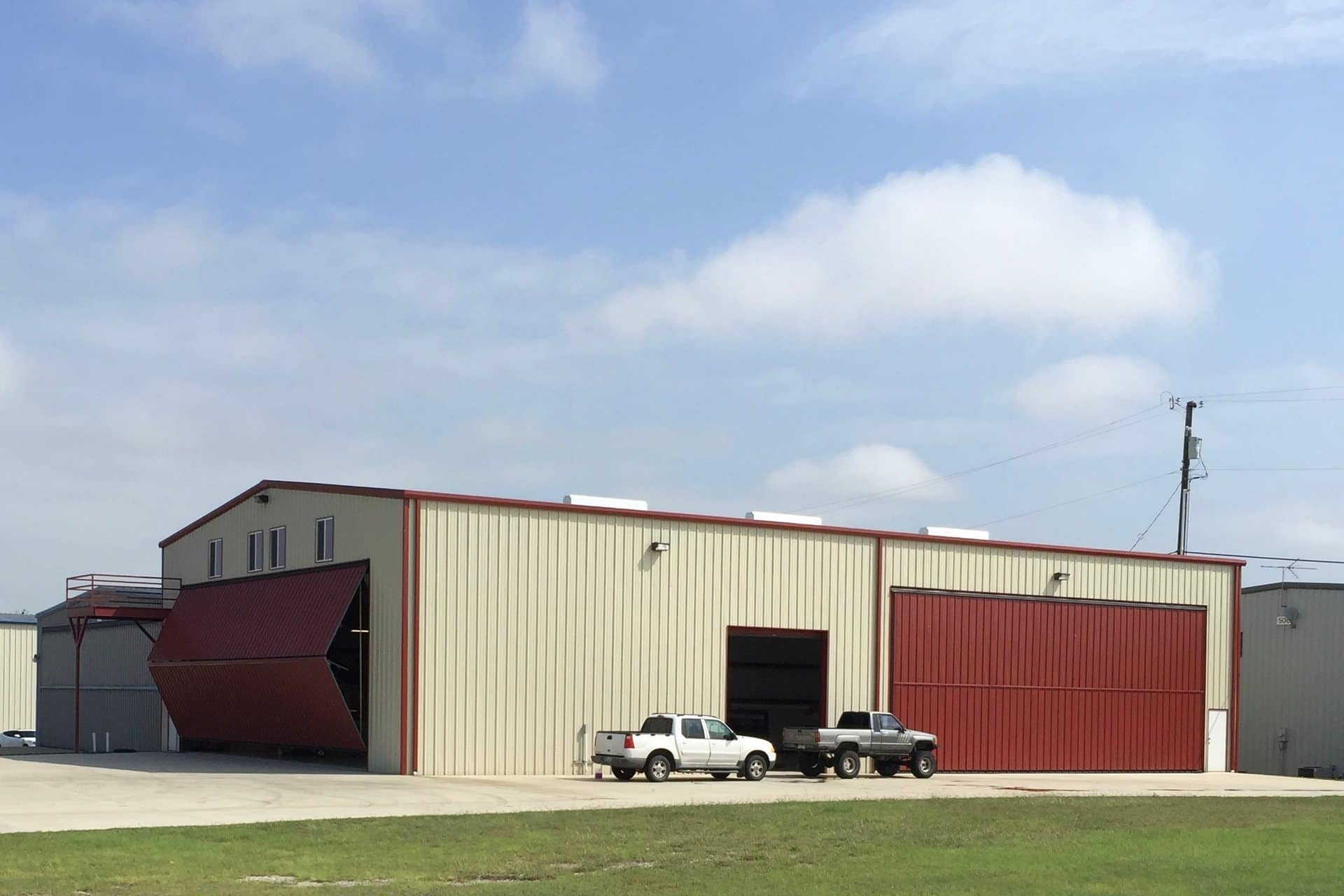 aircraft hangar two bifold doors one open red and cream metal on apron