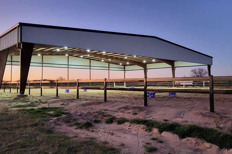 covered riding arena open sided steel over sand footing at dusk