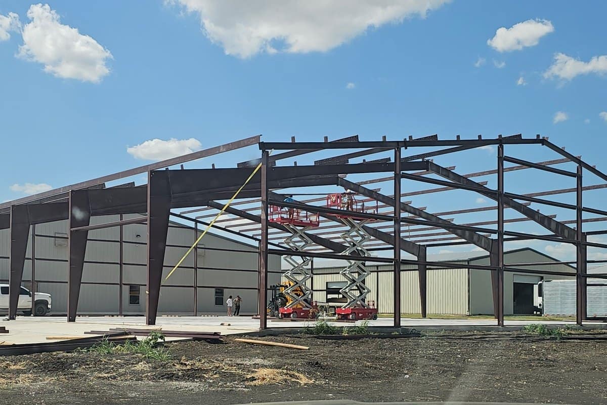 red iron gable frame bare with scissor lifts clear day
