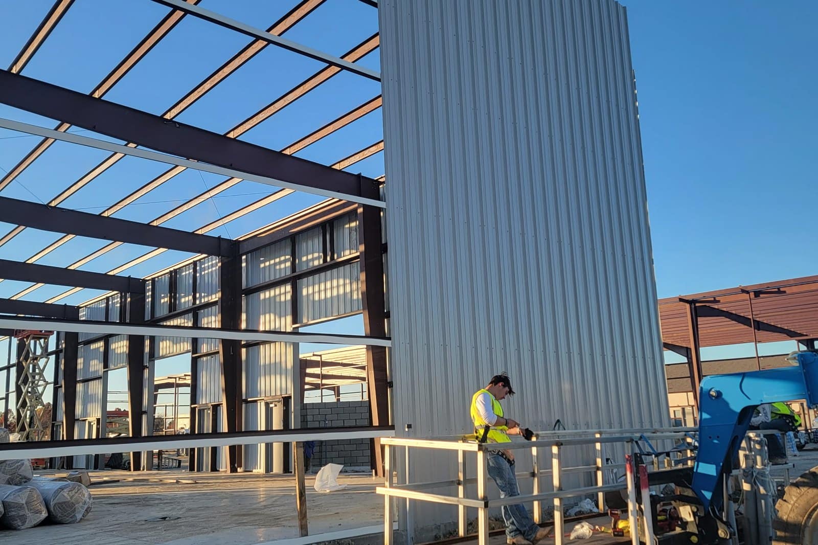 wall panel installation worker on lift clear span frame behind