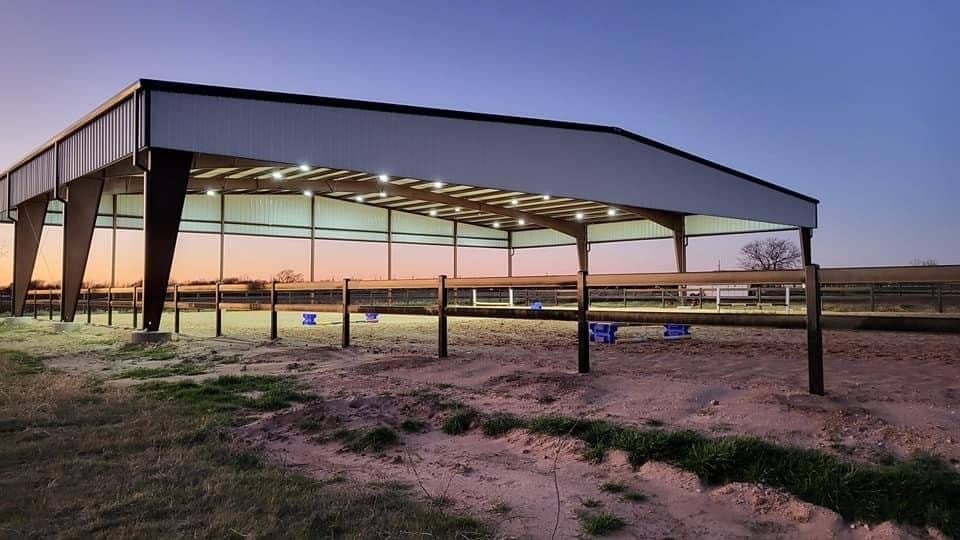covered riding arena open sided steel over sand footing at dusk