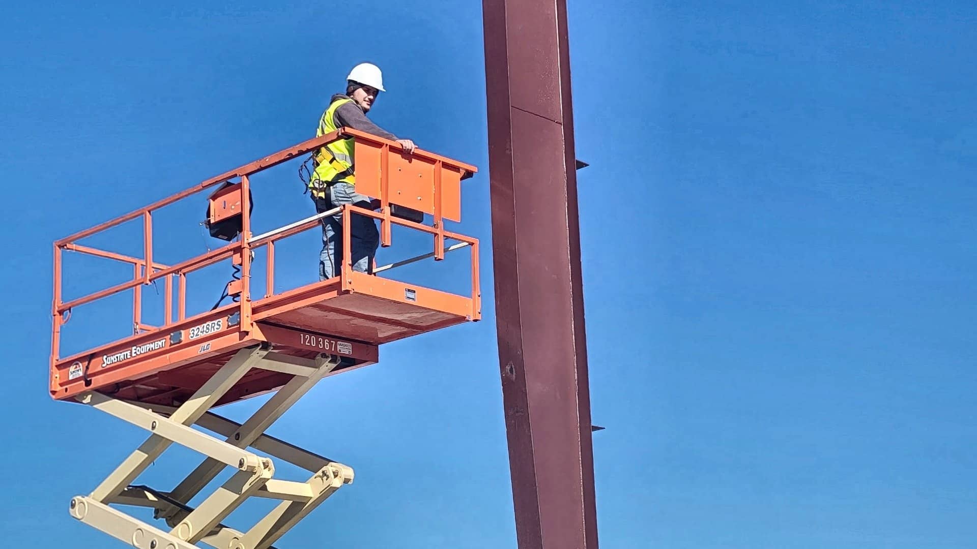 steel erection ironworker on scissor lift at red iron column