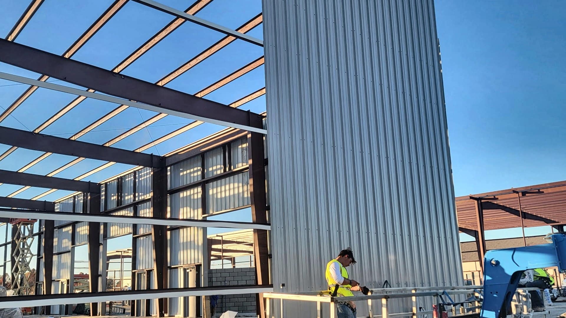 wall panel installation worker on lift clear span frame behind
